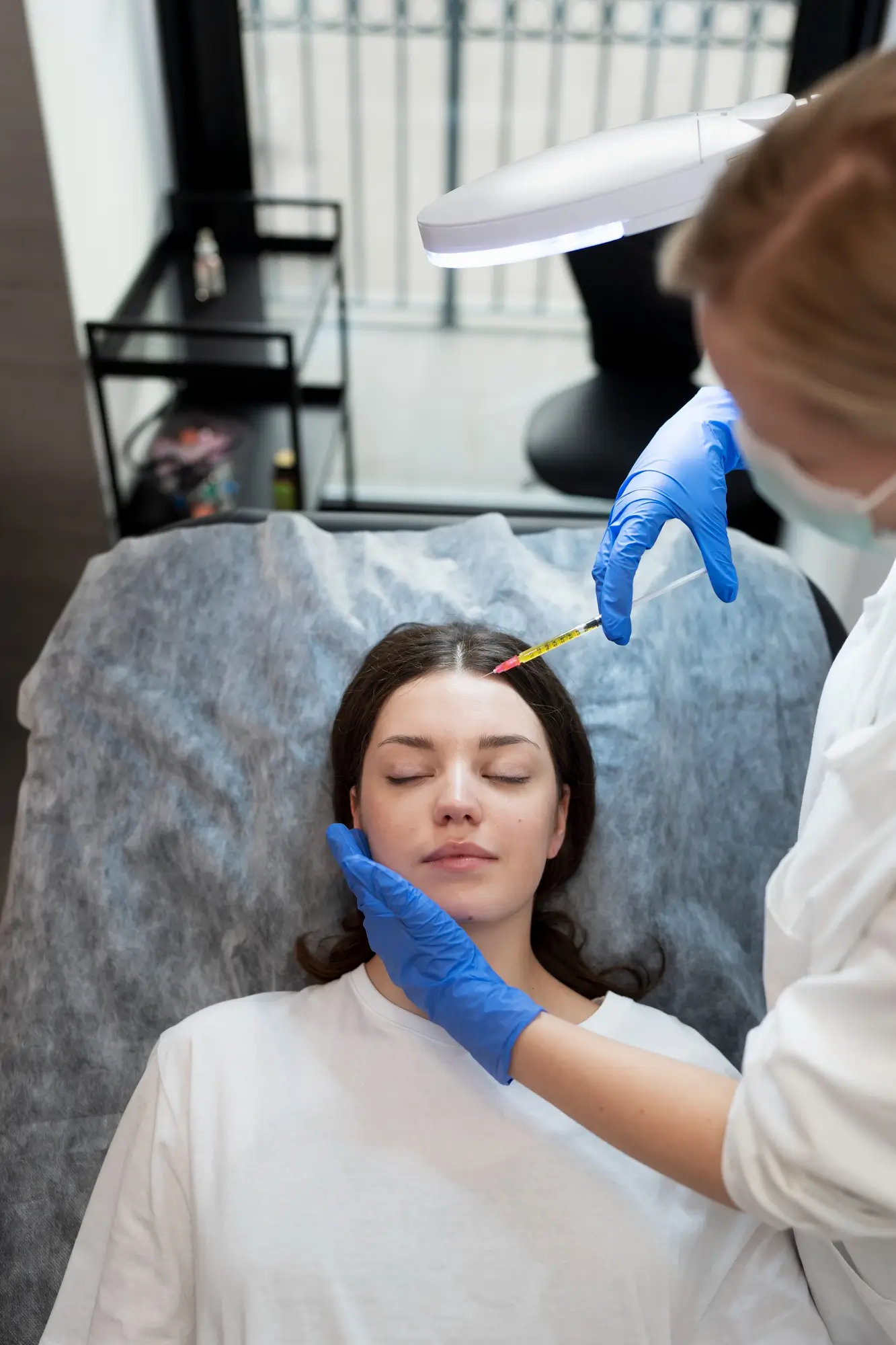 Smiley young woman getting botox injection Smiley young woman getting botox injection